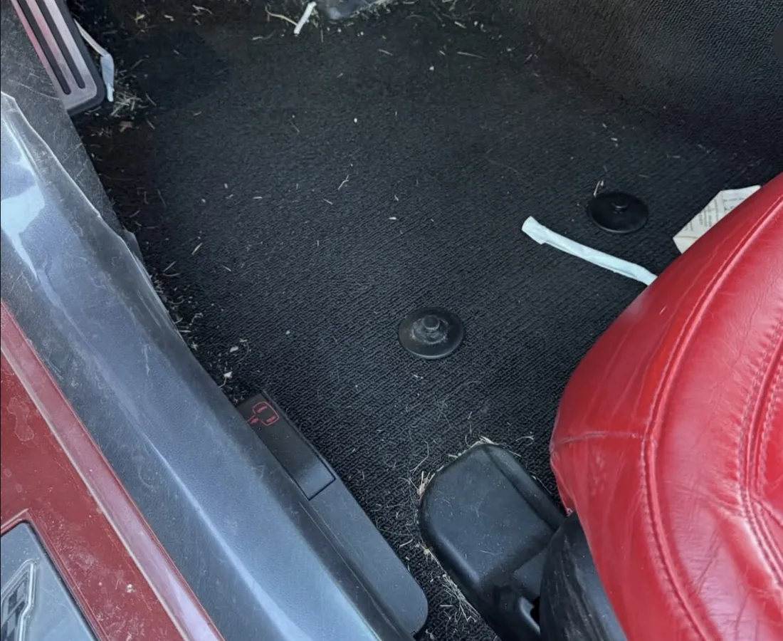 Corvette driver's footwell before detailing — debris and dirt ground into the carpet